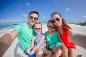 joven y hermosa familia tomando selfie en la playa foto