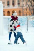 adorable niña con madre patinando en pista de hielo con madre foto