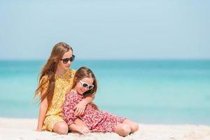 Little happy funny girls have a lot of fun at tropical beach playing together. photo