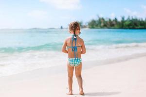 Adorable little girl have fun at tropical beach during vacation photo