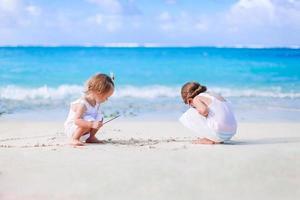 Two kids making sand castle and having fun at tropical beach photo