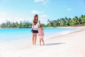 Beautiful mother and daughter on the beach enjoying summer vacation. photo