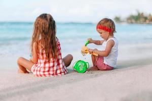 Two kids making sand castle and having fun at tropical beach photo