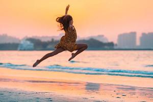 Adorable happy little girl on white beach at sunset. photo