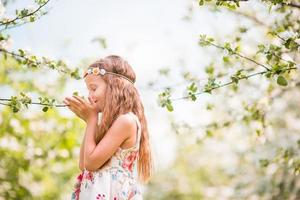 adorable niñita en un floreciente jardín de manzanas en un hermoso día de primavera foto