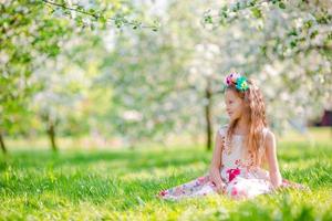 Adorable little girls in blooming apple tree garden on spring day photo