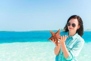 mujer joven feliz con estrellas de mar en la playa blanca en la reserva natural foto