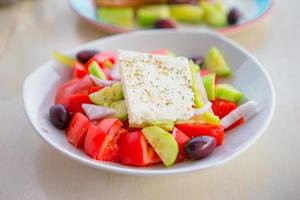 Delicious fresh greek salad served for lunch at outdoor restaurant with beautiful view on the sea and port photo