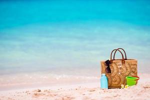 Beach accessories - straw bag, suncream bottle and red sunglasses on the beach photo