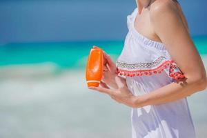 Suncream bottle in female hands on the beach. photo