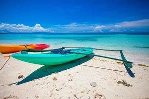 Small boat on the white sandy tropical beach and turquiose ocean photo