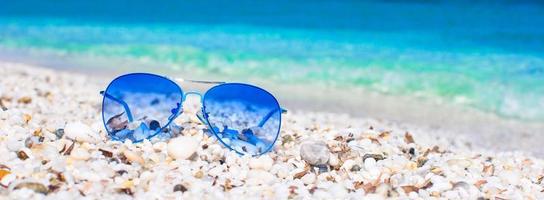 Closeup of colorful blue sunglasses on tropical beach photo