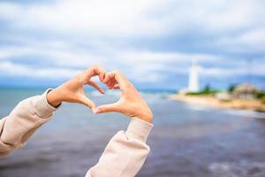 manos femeninas en forma de corazón contra el faro foto