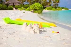 castillo de arena en la playa blanca con juguetes de plástico para niños en la isla perfecta foto