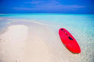 tabla de surf roja en la playa de arena blanca con agua turquesa foto