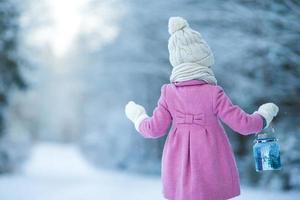 Adorable girl with lamp and candle in winter on Xmas eve outdoors photo