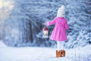 Back view of adorable girl with flashlight on Christmas outdoors photo