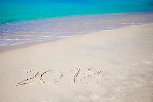 2018 handwritten on sandy beach with soft ocean wave on background photo