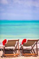 Sun loungers with Santa hat at tropical beach with white sand and turquoise water photo