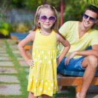 Close up little girl background her young dad at the swimming pool photo