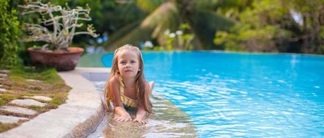 Little adorable girl in the swimming pool looks at camera photo