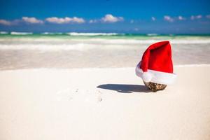 Santa hat at coconut on a white sandy beach photo