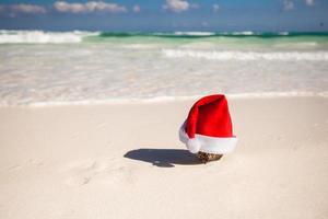Christmas hat at coconut on a white sandy beach photo