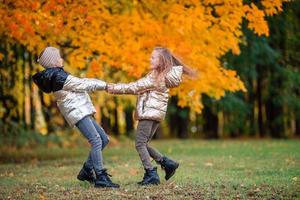 Little adorable girls at warm sunny autumn day outdoors photo