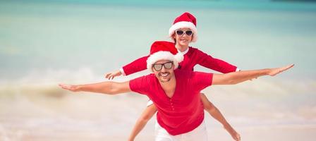 padre e hija con sombrero de santa se divierten en la playa tropical foto