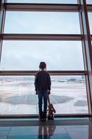 Little girl in airport near big window while wait for boarding photo