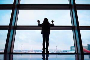 Little girl in airport near big window while wait for boarding photo