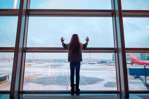 Little girl in airport near big window while wait for boarding photo