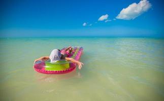 Little cute girl on pink air-bed in Caribbean sea photo