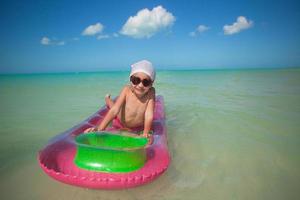 Little cute girl on pink air-bed in Caribbean sea photo