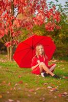 niña feliz ríe bajo el paraguas rojo foto