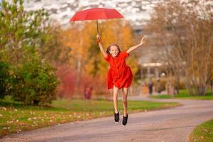 niña feliz ríe bajo el paraguas rojo foto