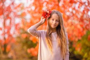 retrato de niña adorable con ramo de hojas amarillas en otoño foto