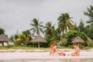 Two kids making sand castle and having fun at tropical beach photo