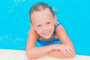 Adorable little girl swimming at outdoor swimming pool photo