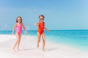 Adorable little girls have a lot of fun on the beach. photo