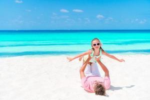 Little girl and happy dad having fun during beach vacation photo