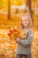 retrato de niña adorable con ramo de hojas amarillas en otoño foto