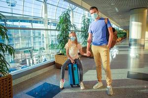 Dad and little girl with nedical masks at airport. Protection against Coronavirus and gripp photo