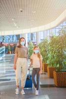 Mother and little girl with nedical masks at airport. Protection against Coronavirus and gripp photo