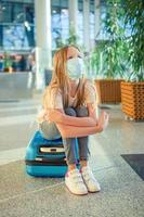 niño pequeño con máscara médica en el aeropuerto esperando el embarque foto