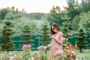 niña en un jardín de flores entre hermosas rosas. olor a rosas foto