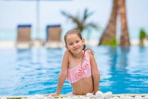 Little happy cute girl in outdoor swimming pool photo