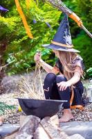 linda niña con traje de bruja en halloween al aire libre. truco o trato. foto