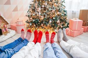 Close up photo of family feet in woolen socks by the christmas tree