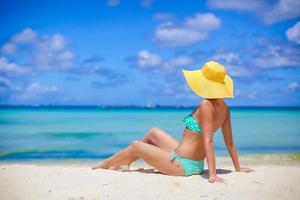 mujer sentada en la playa con sombrero y mirando el océano foto